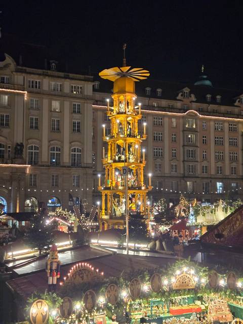 Nighttime market scene with a lit-up structure and crowds.