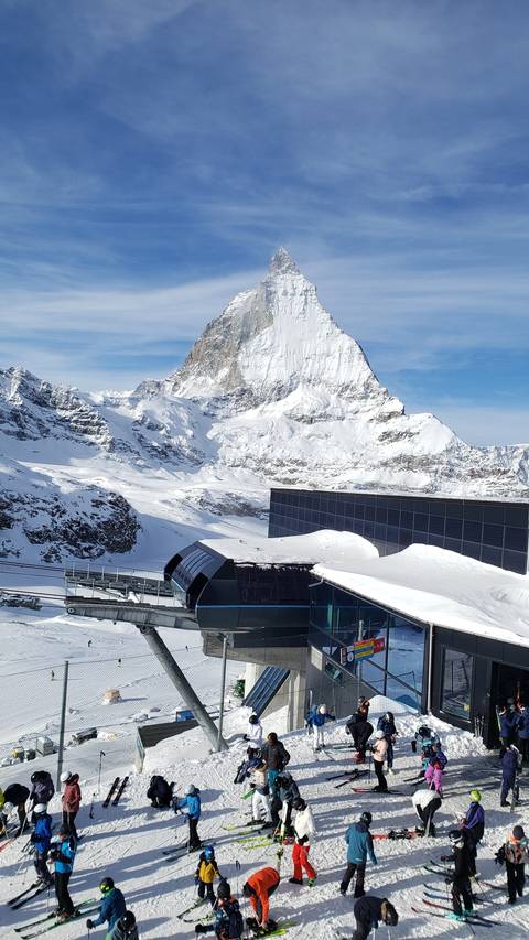 A snowy mountain scene with people and a modern building.