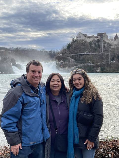 Three people posing with an icy waterfall in the background.