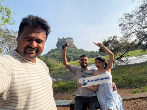 A couple posing in front of Sigiriya rock with a travel sign.