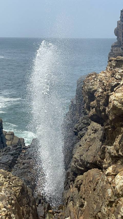 A splash of water hitting rocky cliffs by the sea.