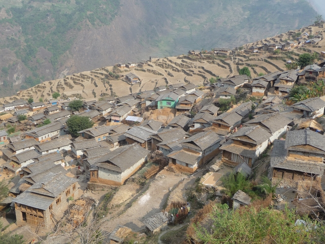       Aerial view of terraced hillside village with rows of stone houses in Nepal.
  