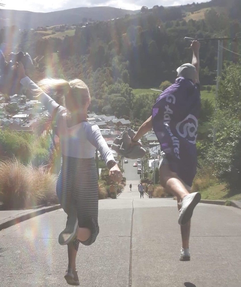 Two people playfully running down a hill with a flag.