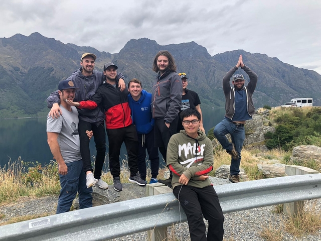      Group of people posing on a mountainous road.
  