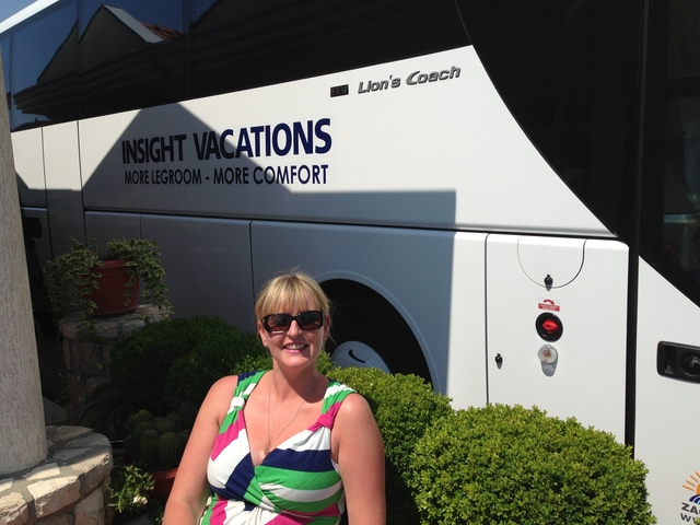 Woman in front of a tour bus, relaxing.