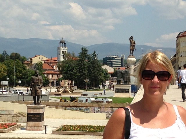 City square with statues and mountainous backdrop.