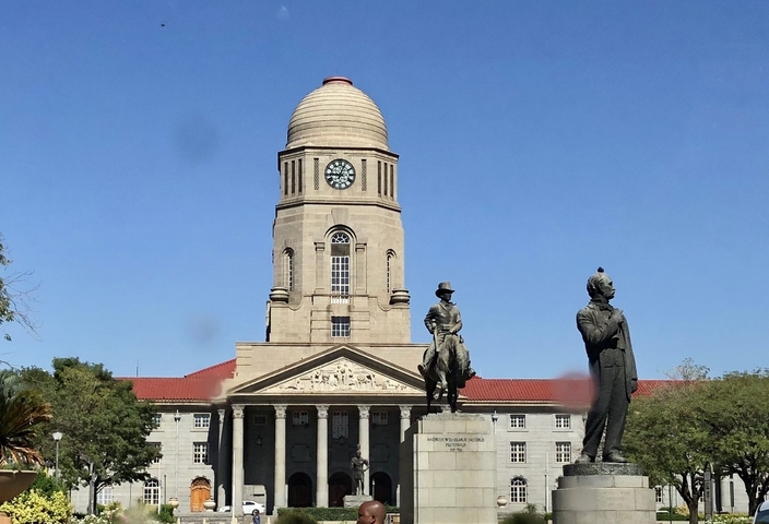       Statue in front of a historic building with a clock tower.
  