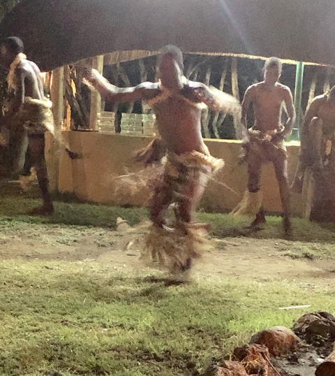       Blurry image of people performing a traditional dance at night.
  