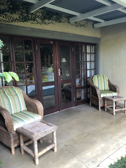       Patio with two wicker chairs and glass doors.
  