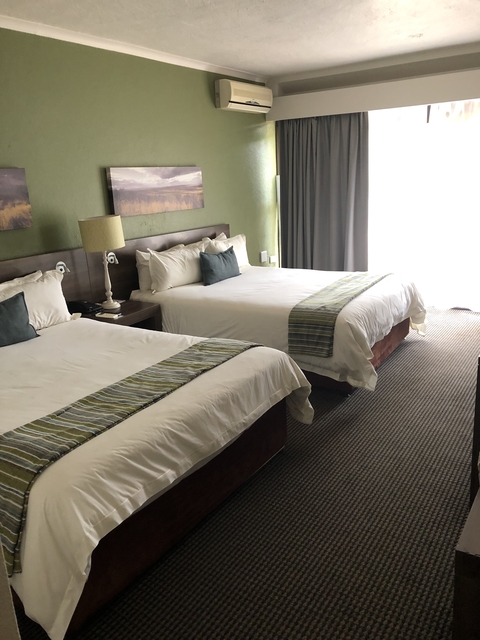       Hotel room with two double beds and large window.
  