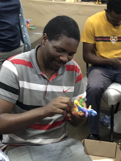 Man sitting and making crafts with colorful material.