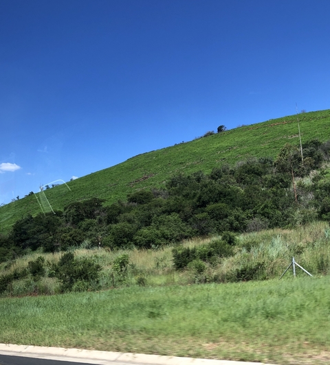      Landscape of a green hill with blue sky.
  