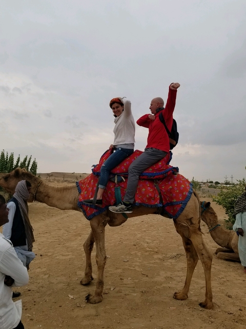 Two people riding a camel in a desert landscape.
