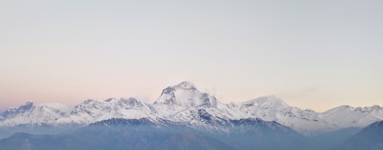       Snow-covered mountains during dawn with a pink hue.
  