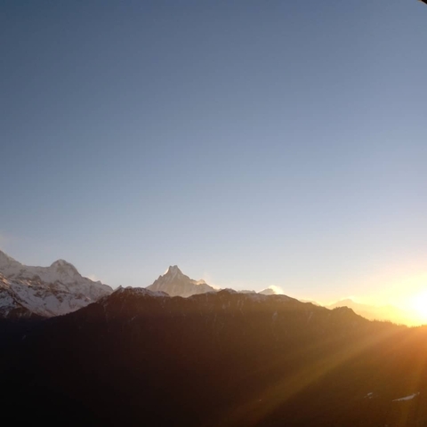       Sun rising over mountain range with clear sky.
  