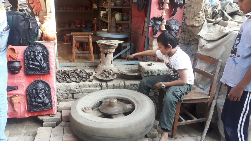       Pottery making by a young boy in a small workshop.
  