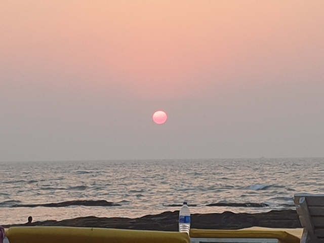 Sunset over a calm ocean with a clear view of the sun near the horizon.