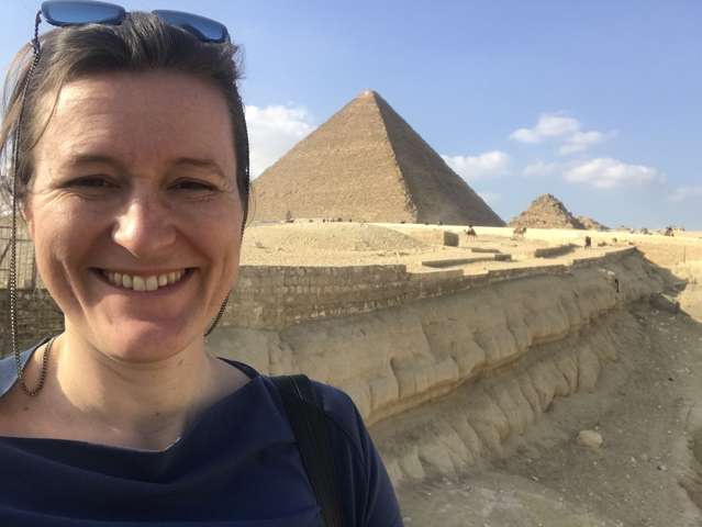 A person smiling with pyramids in the background.