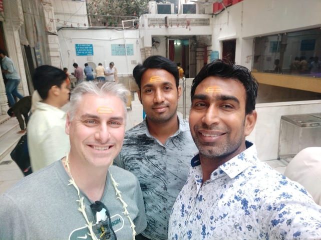 Three people at a religious site with forehead markings.