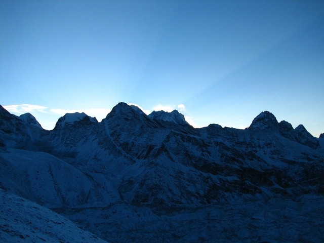      Silhouette of snow-capped mountains at sunrise.
  