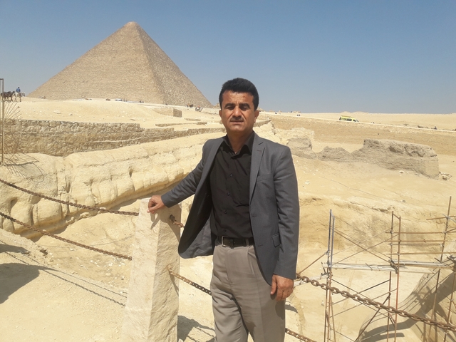 A man posing in front of the Giza pyramids.