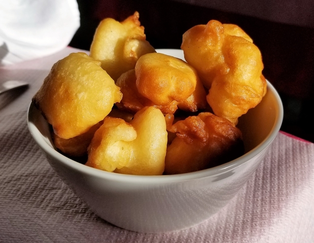       A bowl of golden-brown fried dough bites.
  