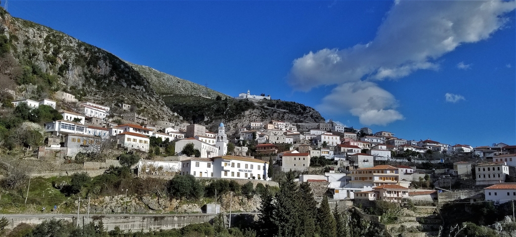       A town built on a hillside under a clear blue sky.
  