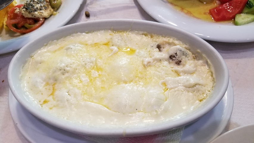       A dish of melted cheese with accompanying sides on a table.
  