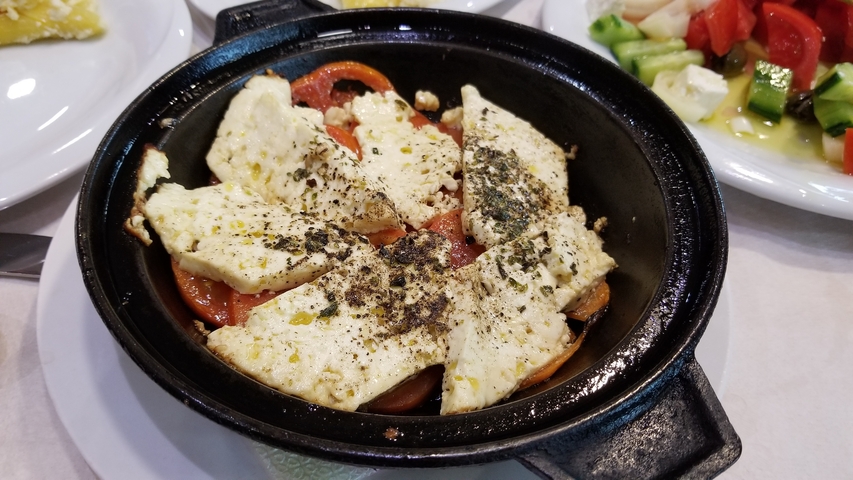       A sizzling dish with vegetables and cheese.
  