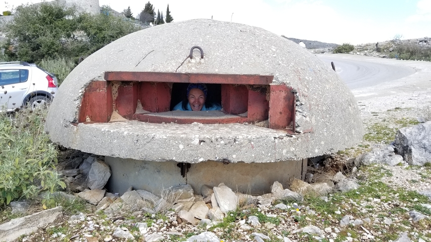       Person peering out of a concrete bunker.
  