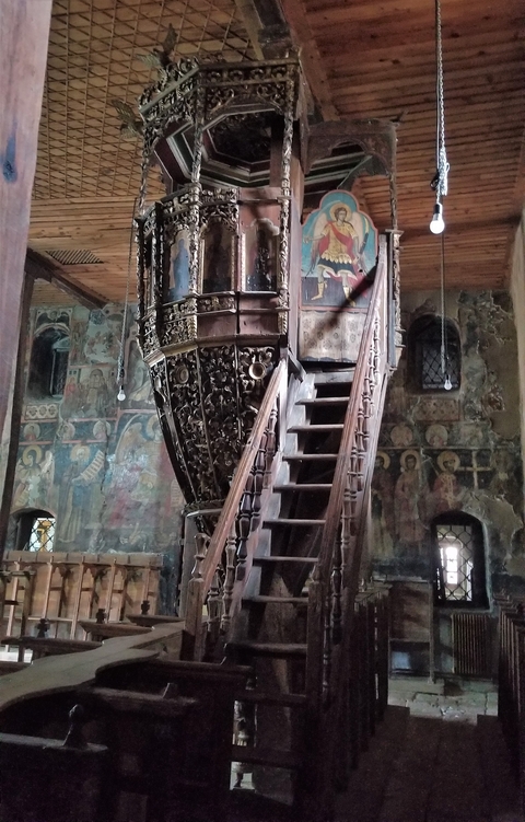       Intricately carved pulpit in an old church with frescoes.
  