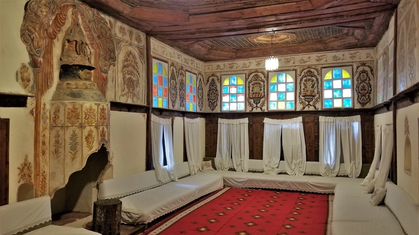       A room with colorful stained-glass windows and white drapery.
  