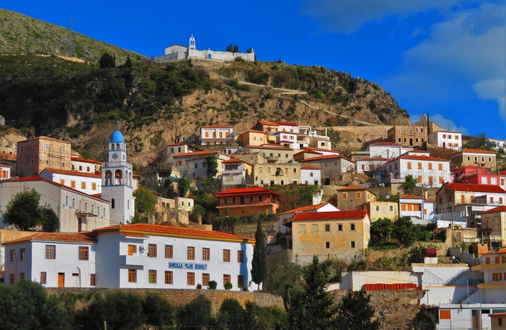       Hillside houses with red roofs in a sunny setting.
  