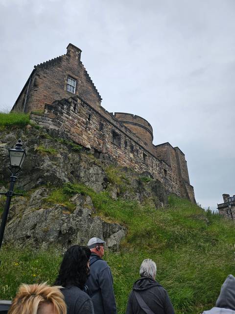       Stone castle on a hill seen from below.
  