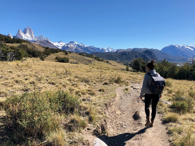 Hiker on a trail with mountains in the distance.