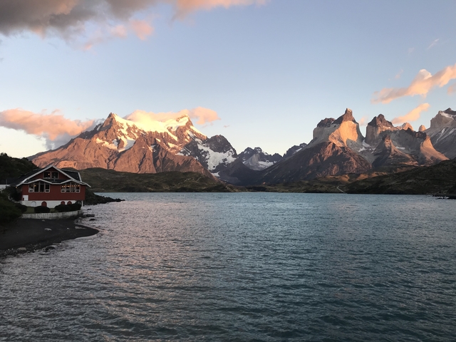 Lakeside view of mountains at sunrise with a lodge.