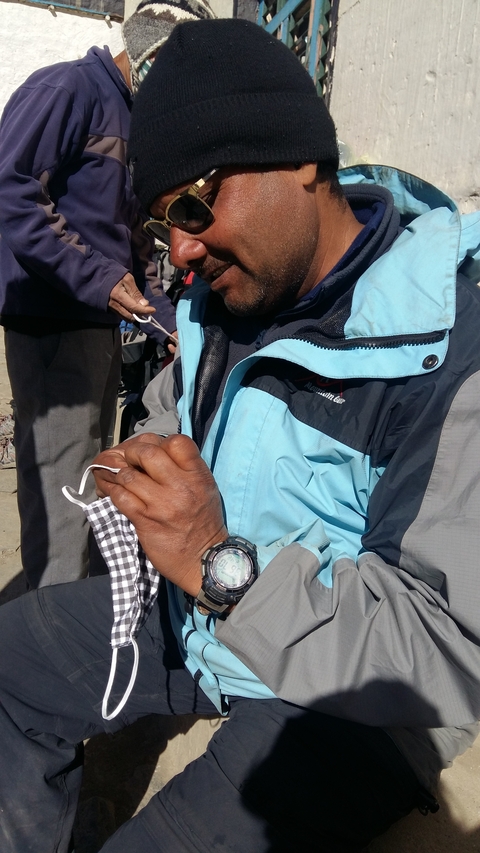 Man adjusting clothing details in an outdoor setting.