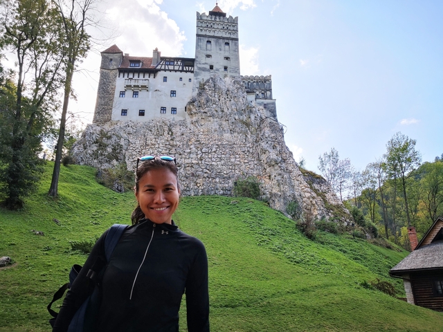Woman posing in front of a castle on a hill.