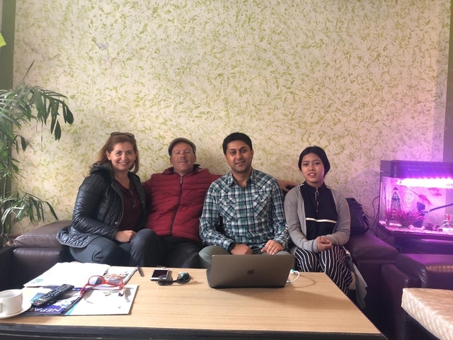 Four people sitting on a couch with a fish tank in the background.