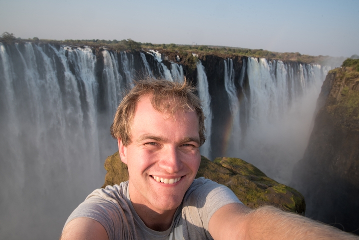       Person taking a selfie with a large waterfall in the background
  
