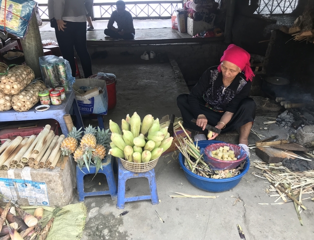       Woman preparing food at a market stall with various goods
  