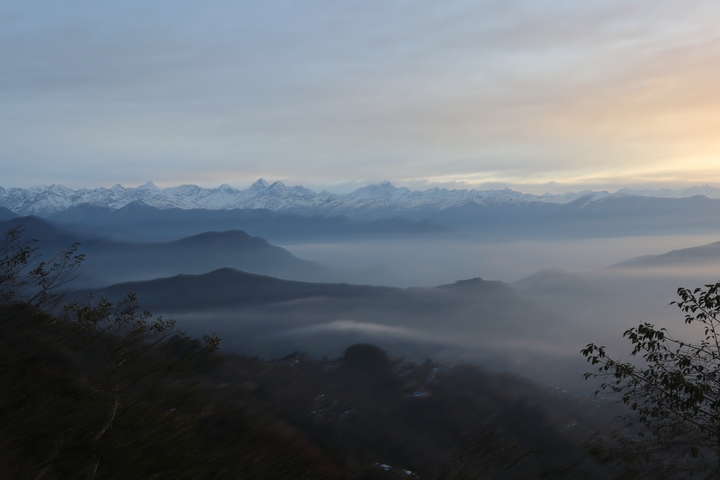       Scenic mountain range with mist and snow-covered peaks at sunrise.
  