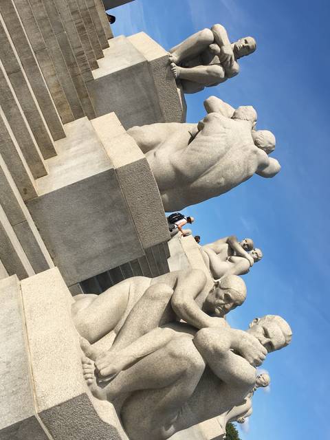Statues in a park with people walking around.