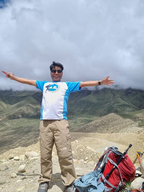       Person with arms outstretched overlooking a mountainous landscape.
  