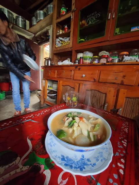 Bowl of soup on a table in a rustic kitchen setting.