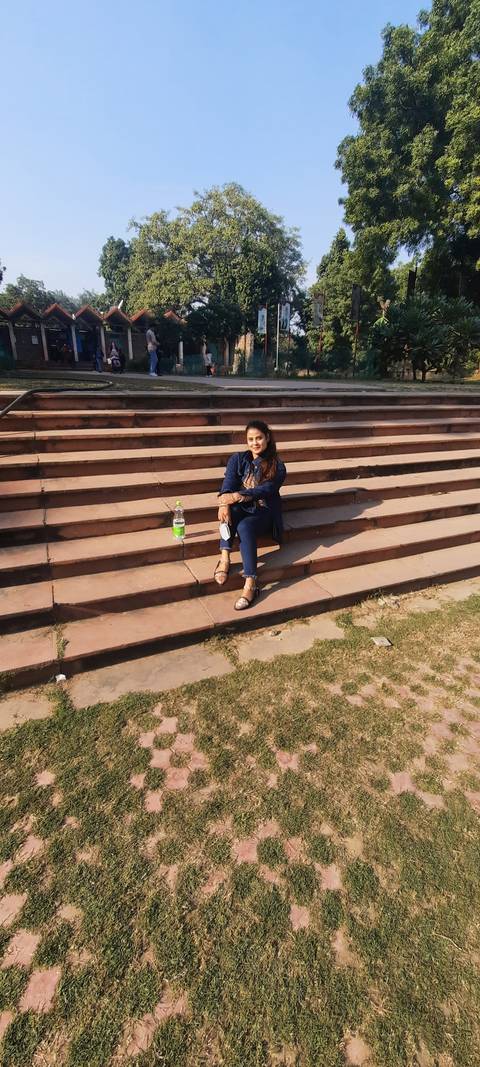      Woman sitting on steps with trees in the background
  
