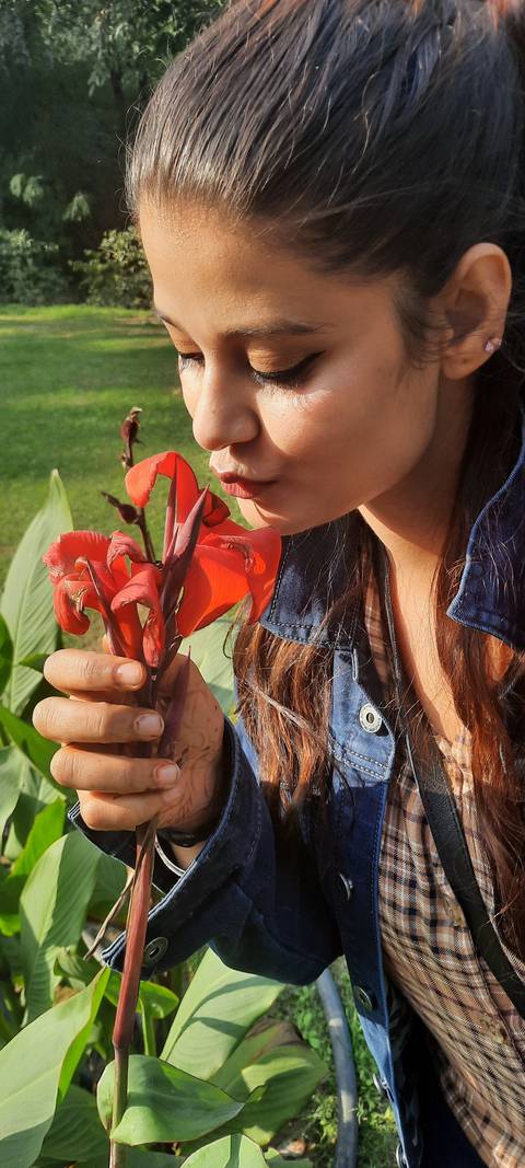       Woman smelling a red flower
  