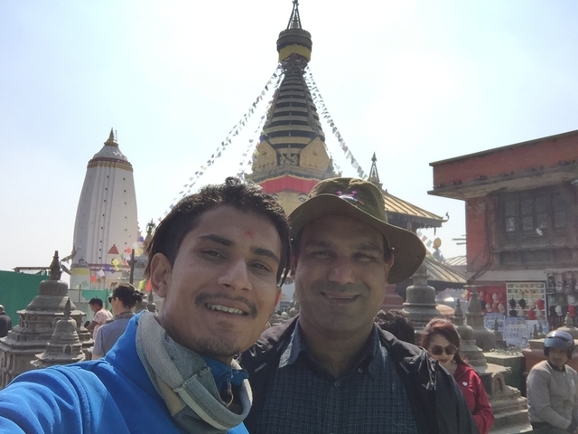       Two people taking a selfie at a temple with stupa structures.
  