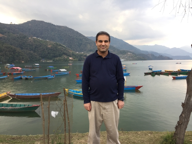       A person standing by a lake with colorful boats.
  