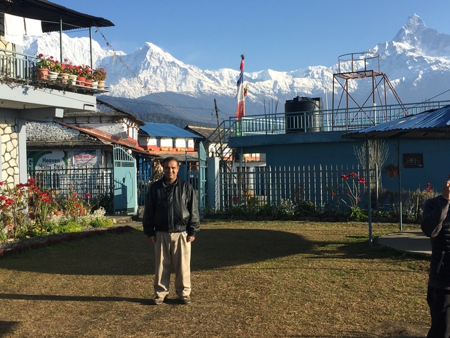       A person posing in a garden with mountains in the background.
  